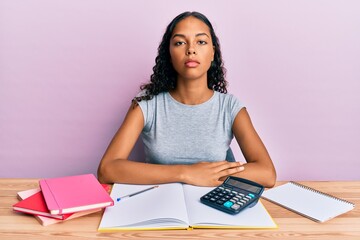 Poster - Young african american girl accountant working at the office relaxed with serious expression on face. simple and natural looking at the camera.