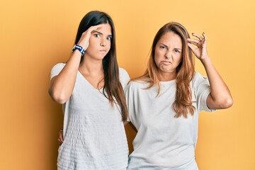 Wall Mural - Hispanic family of mother and daughter wearing casual white tshirt worried and stressed about a problem with hand on forehead, nervous and anxious for crisis