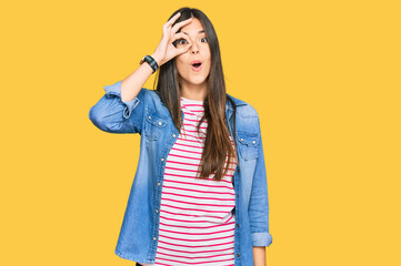 Sticker - Young brunette woman wearing casual clothes doing ok gesture shocked with surprised face, eye looking through fingers. unbelieving expression.