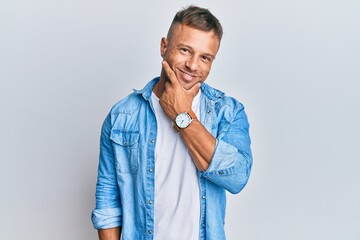 Poster - Handsome muscle man wearing casual denim jacket looking confident at the camera smiling with crossed arms and hand raised on chin. thinking positive.