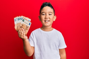 Canvas Print - Little boy hispanic kid holding bunch of 50 euro banknotes looking positive and happy standing and smiling with a confident smile showing teeth