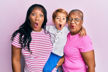 Wall Mural - Hispanic family of grandmother, mother and son hugging together scared and amazed with open mouth for surprise, disbelief face