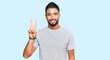 © Krakenimages.com - Young man with beard wearing casual grey tshirt showing and pointing up with fingers number two while smiling confident and happy.