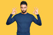 © Krakenimages.com - Young man with beard wearing casual blue winter sweater relax and smiling with eyes closed doing meditation gesture with fingers. yoga concept.