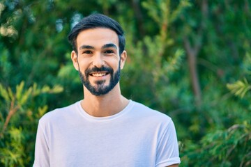 Young hispanic man smiling happy standing at the park.