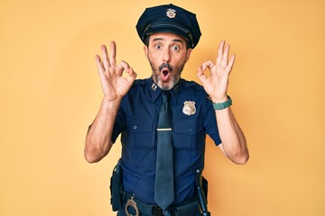 Poster - Middle age hispanic man wearing police uniform looking surprised and shocked doing ok approval symbol with fingers. crazy expression