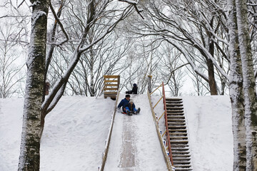 Children in the park in winter. Kids play with snow on the playground. They sculpt snowmen and slide down the hills.