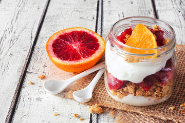Wall Mural - healthy red blood orange parfait in a mason jar over a rustic white wood table background