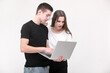 © Andriy Medvediuk - Two serious teenager guy and girl are using laptop and discussing something on white background in studio. Male and female surprised