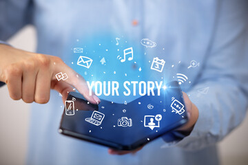 Businessman holding a foldable smartphone with YOUR STORY inscription, social media concept