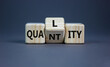 Quality over quantity symbol. Turned cubes and changed the word 'quantity' to 'quality'. Beautiful grey table, grey background, copy space. Business and quality over quantity concept.