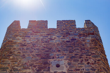 Low angle shot of a historic medieval stone castle on background of the clear blue sky