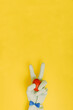 Gloved hand holds an Easter red egg on a trendy yellow background. Dressy rabbit with copy space. Minimal Easter corona virus concept.