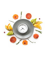 An empty plate with alarm clocks and fresh sliced fruit juicy around. Flat lay for menu background and food mode