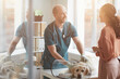 © Seventyfour - Portrait of mature veterinarian examining dog at vet clinic and smiling while talking to young woman, scene lit by sunlight, copy space