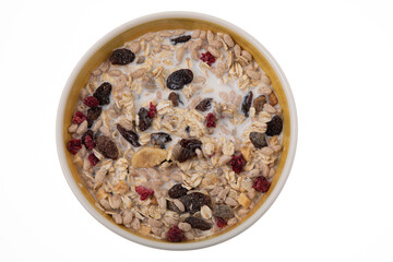 Breakfast oatmeal with nuts and dried fruits in yellow bowl with milk on white background