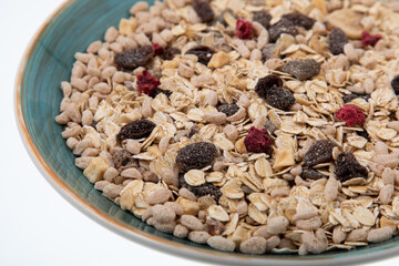 Breakfast oatmeal with nuts and dried fruits in blue bowl on white