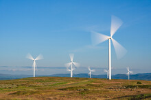 Spinning Wind Turbines Against Blue Sky Shown In Slow Motion To Capture The Effect Of The Moving Blades