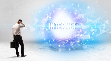 Wall Mural - Rear view of a businessman standing in front of INTERNET inscription, modern technology concept