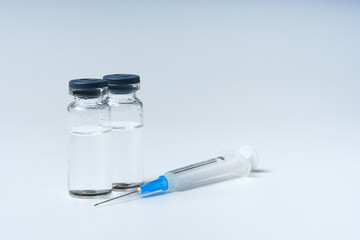 Close up glass vial with flu vaccine and syringe with needle. The concept of vaccination or preventive treatment of injection diseases.