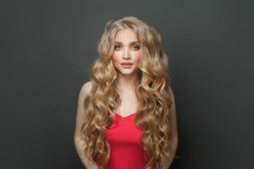 Wall Mural - Cute blonde woman with long curly hair in red dress on black