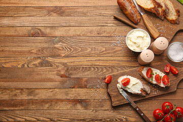 Bread with tasty cream cheese and tomatoes on wooden background