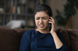 © fizkes - Upset young Indian woman talk on smartphone at home feel distressed disappointed with bad news. Unhappy millennial mixed race ethnicity female frustrated by negative message having cell call.