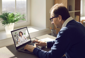 Male patient consulting online doctor at home. Mature man using laptop computer and communicating with nurse or general practitioner. Telemedicine, virtual visit to clinic, video conference concept