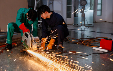 teamwork, safety working concept. Engineer working in a workshop of a factory. Mechanic dress safety use a cutting tool to cut a metal. Nice spark from cutting iron