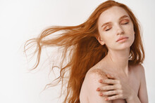 Close-up Of Tender Young Woman With Long Natural Red Hair Flying In Air, Close Eyes And Relaxing On White Background, Standing Naked, Showing Perfect Pale Skin And Ginger Haircut