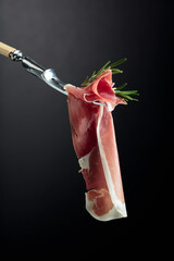 Wall Mural - Sliced prosciutto with rosemary on a fork.