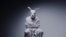 Madness and mental illness concept. Scary, crazy person in animal mask tied in a white room. Nightmare, psychosis. Paranoia and depression concept, isolated madman.