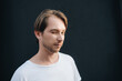 © Natalia - Portrait of european winking man in white t-shirt at dark wall