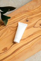 Wall Mural - blank white cosmetics plastic tube mockup and green leaf on wooden board on bathroom table. natural 