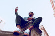 © Jaime - black boy sitting on ladder using mobile phone