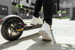 © Oleksandr Kozak - female foot in white sneakers are riding electric scooter in urban background