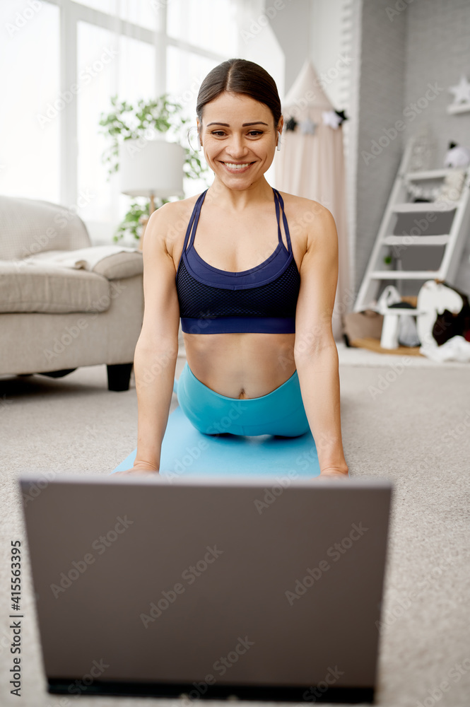 Smiling girl sits on floor, online fit training - obrazy, fototapety, plakaty 