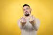 © Irene - Handsome man with beard wearing sweater over yellow background showing middle finger doing fuck you bad expression, provocation and rude attitude. screaming excited
