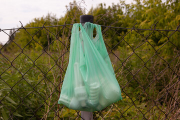 Canvas Print - Closeup view of various light bulbs in a green bag hanging from a metal fence outside