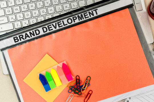 Brand Development. Business concept on folder. Composition with folder, coffee cap, cell phone and laptop on office desk.