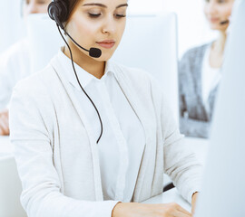 Wall Mural - Call center. Group of diverse operators at work. Beautiful woman in headset communicating with customers of telemarketing service. Business concept