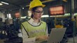 © Ha-nu-man - Asian employee holding open laptop at manufacturing plant. Looking forward to the industry.