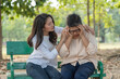 © Supachai - Senior Asian  woman feeling headache with her daughter help and support while sitting relaxed on benches at the park