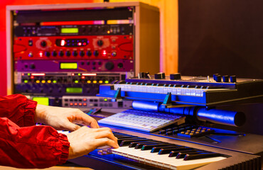 Wall Mural - musician hands playing electric piano with soundmodule background in recording studio