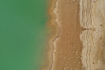 Aerial top view pattern of clear river water and sand on the river bank