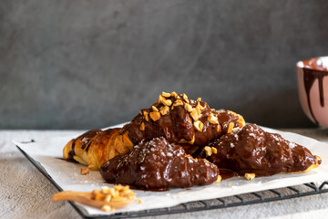 Wall Mural - Dark chocolate croissants with nut and flower of salt on top in vintage dark stone background. Tasty and freshly croissants. 