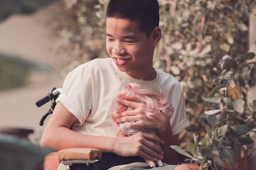 Asian disability child on wheelchair looking, talking with the girl doll in hands,Lifestyle of special child in the education age,Happy disabled kid concept, Sometime toy is best friend in alone mood.