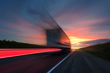 motion blur. a large truck is driving along the highway at high speed. sky with bright red clouds. d