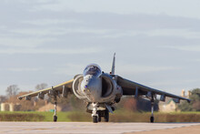 Harrier Jump Jet Taxis Towards The Camera Crossing The Runway. Small Vertical Take And Landing Strike Fighter