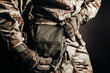 © breakermaximus - Photo of soldier in camouflaged uniform and tactical gloves using leg bag on black background.